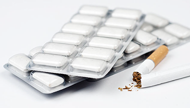 Image of cigarette broken in half with nicotine gum next to it.