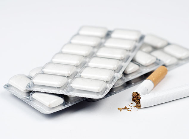 Image of cigarette broken in half with nicotine gum next to it.
