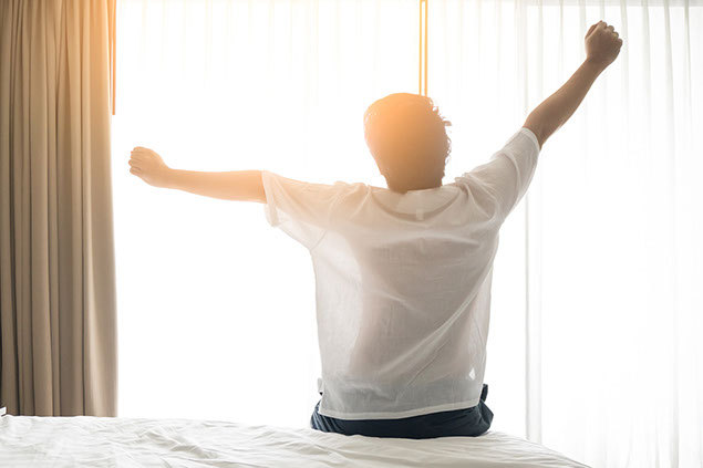 Image of man waking up and stretching in the morning.